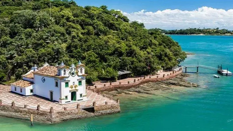 Igreja de Nossa Senhora de Loreto na ponta da Ilha dos Frades, cercada por mar verde